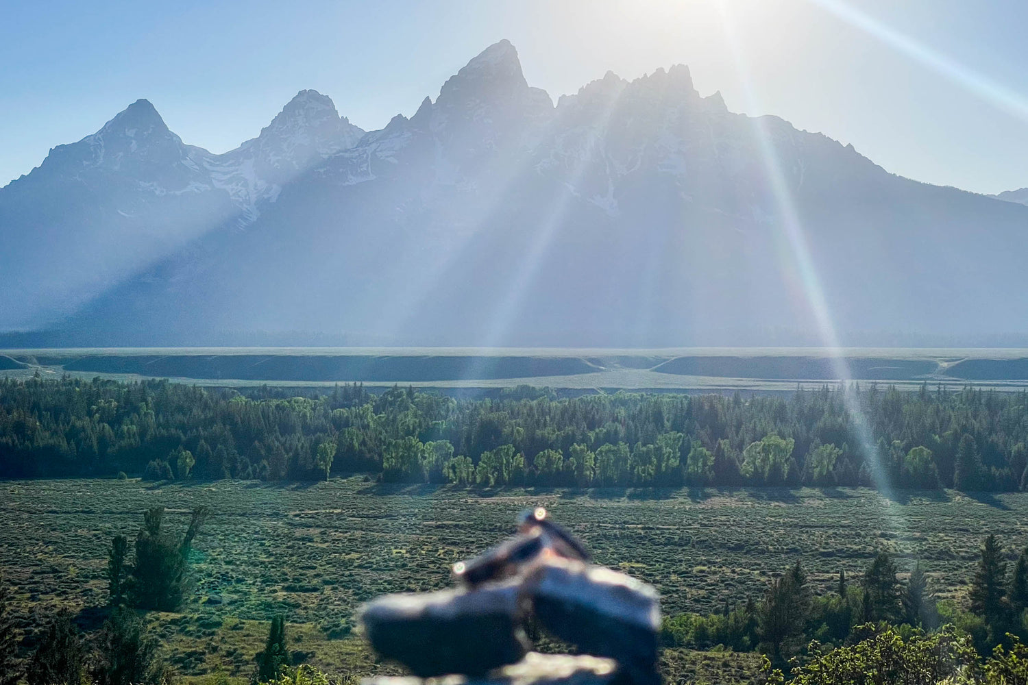 A scenic view of Banff National Park with sunbeams shining over the mountains, while a matching rose gold ring set with Banff-collected stones rests out of focus in the foreground—capturing the connection between love and the natural world.
