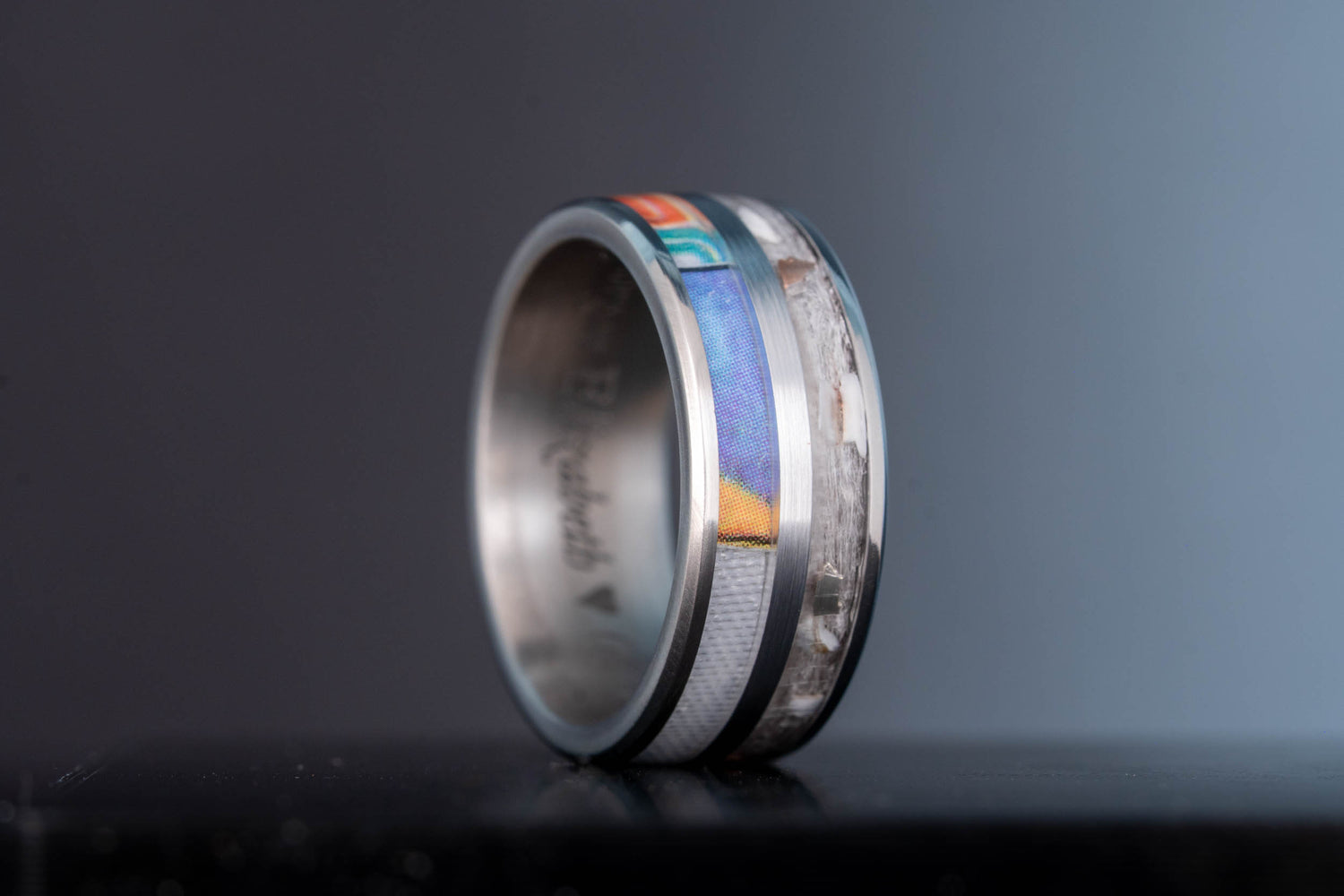 Finished custom titanium keepsake wedding ring featuring layered inlays made from personal materials.