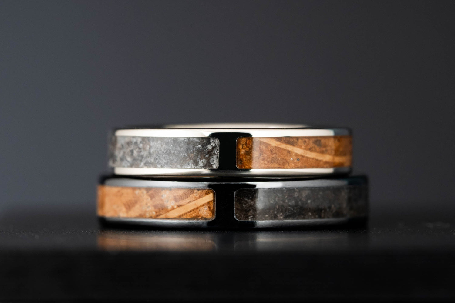 Stacked view of handmade wedding rings with split inlay design, combining crushed stone and wine barrel oak in gold and titanium bands.