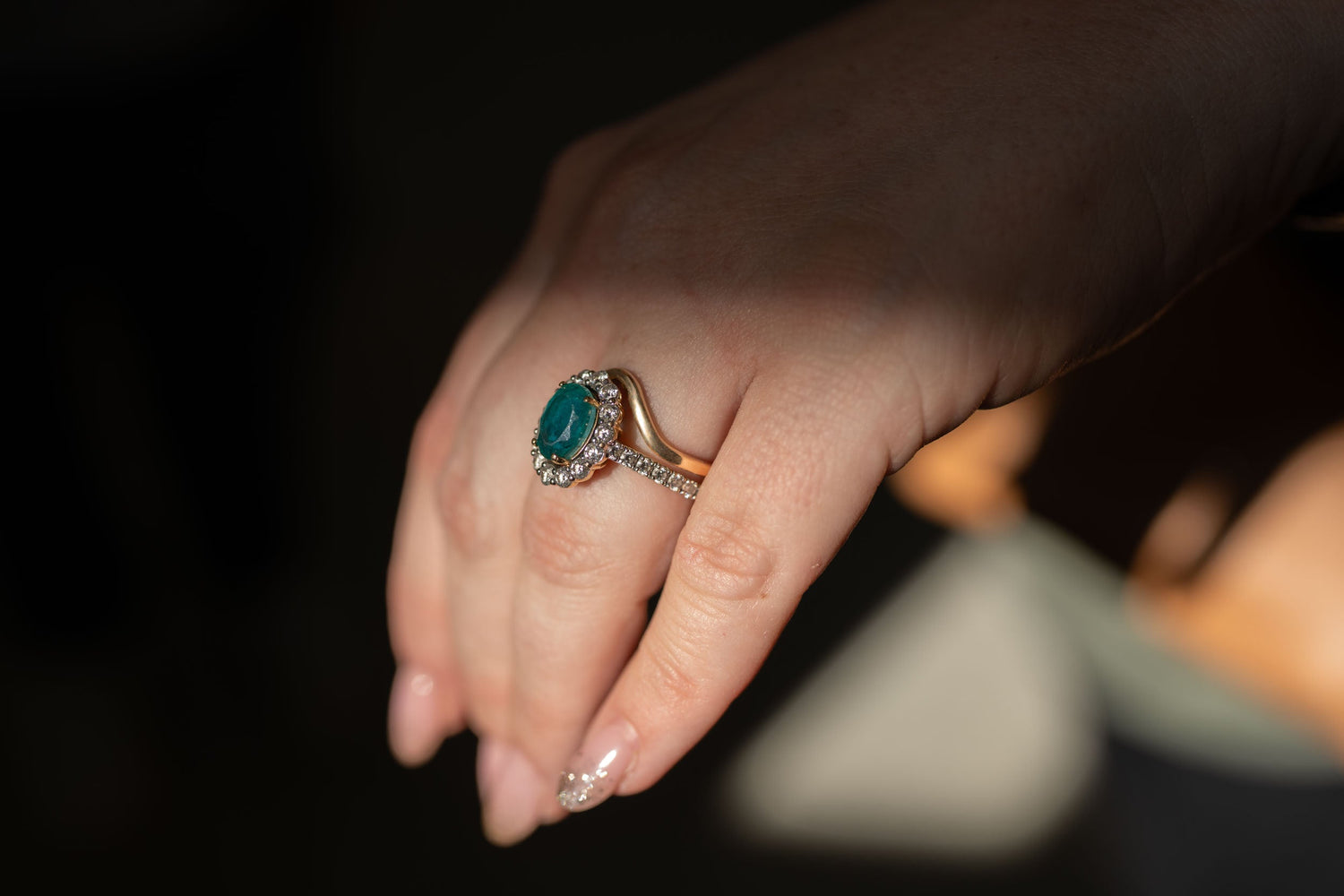 Contour wedding band fitted around emerald halo engagement ring on hand