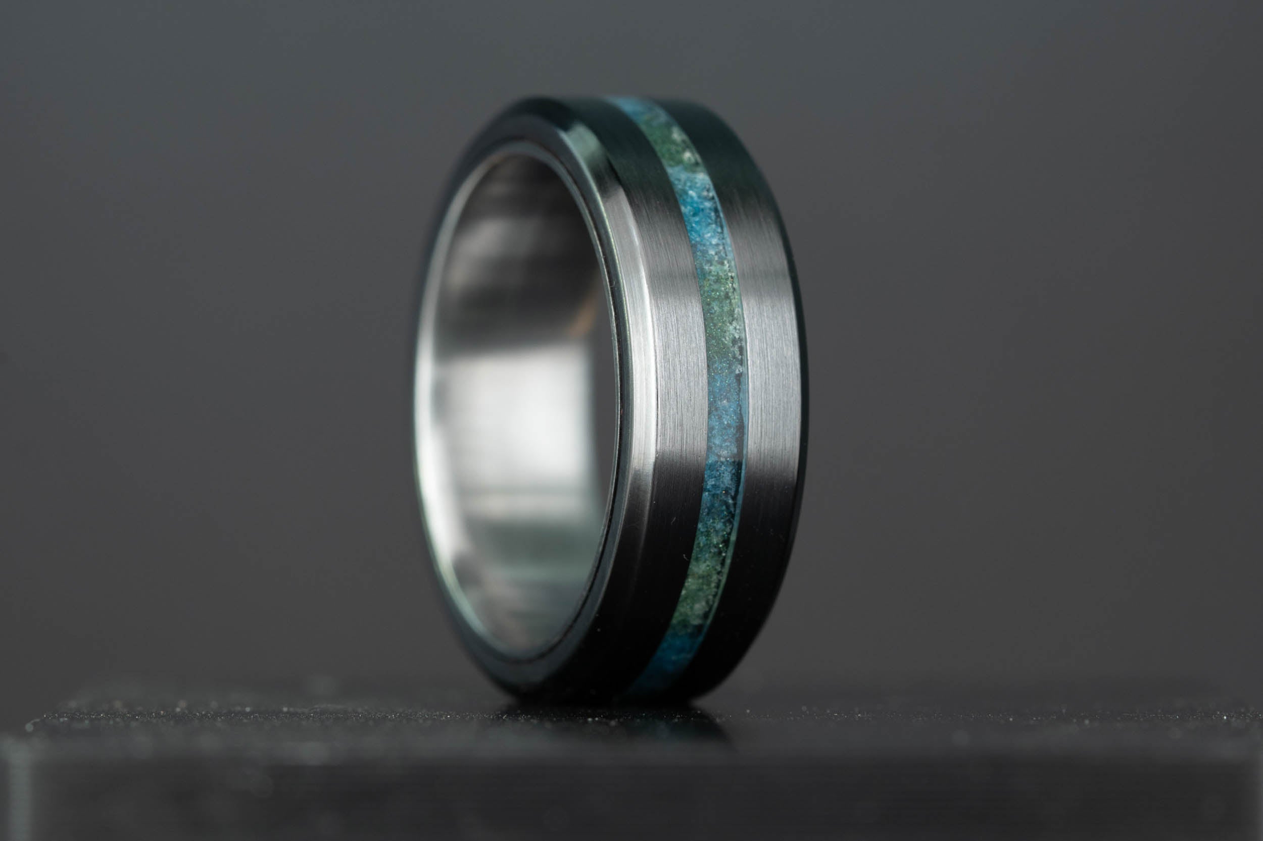 Custom black titanium wedding ring with crushed emerald and sapphire inlay by Honest Hands Ring Co.